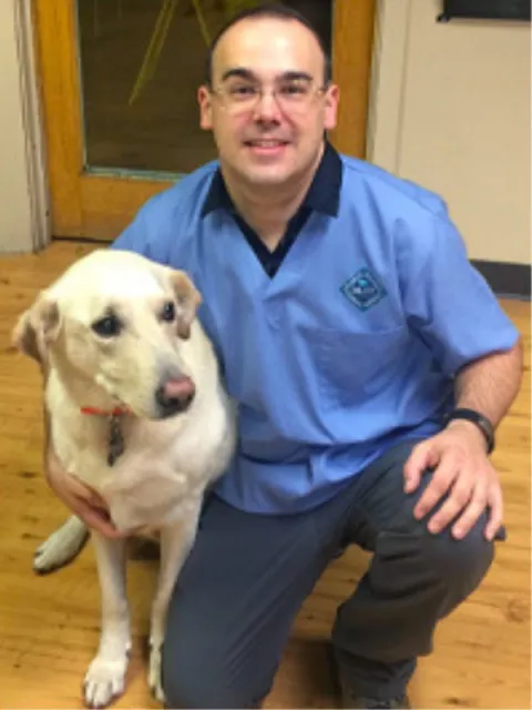 Dr. Keith Harrington kneeling beside a yellow Labrador